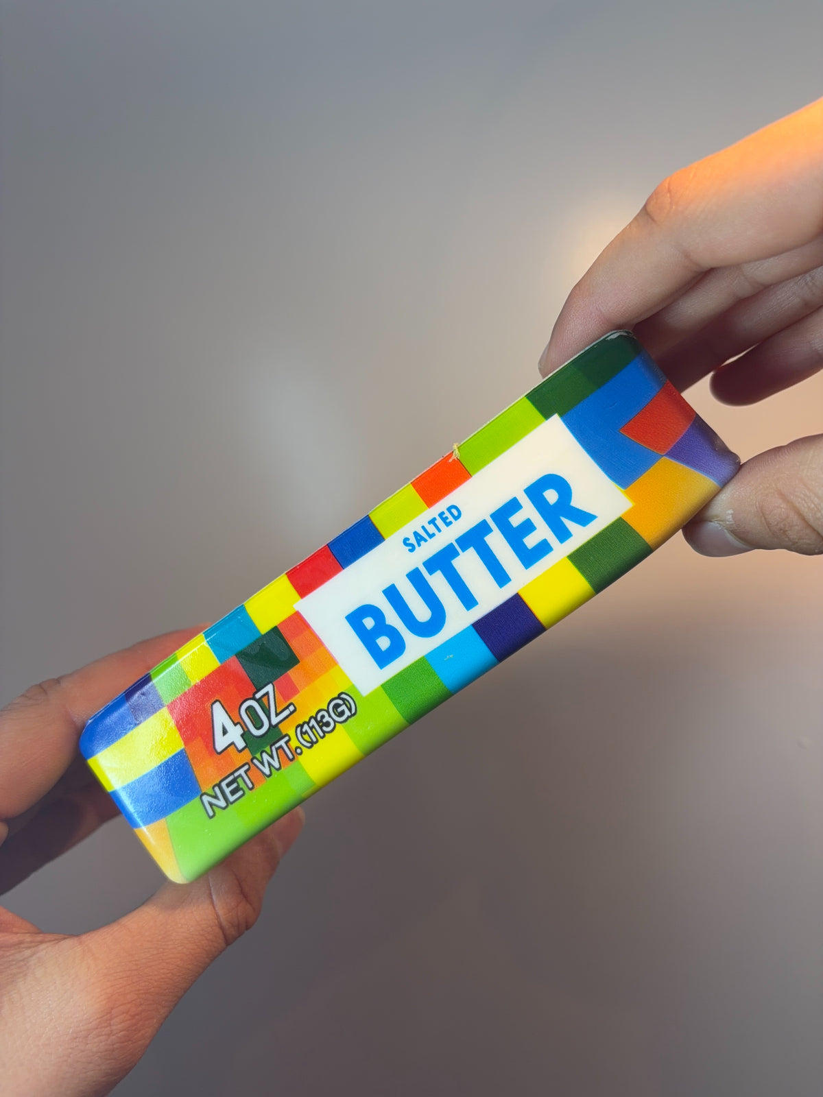 Multicoloured butter squishy held in a hand